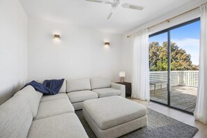 Uma sala de estar moderna com sofá seccional, uma mesinha lateral e um ventilador de teto.