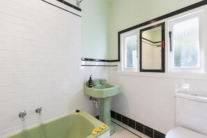 A bathroom with a green bathtub, a white toilet, and a sink with a mirror above it. - South Moffat - Spectacular Views, Modern Styling (Lorne)