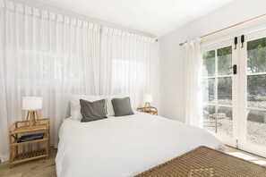 A bedroom with a large bed, two bedside tables, a window with curtains, and a view of the outdoors. - South Moffat - Spectacular Views, Modern Styling (Lorne)
