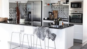 A modern kitchen with a central island, stainless steel appliances, and a tiled backsplash. - Nordic spanish pool villa (Campello)