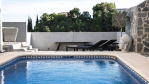 A swimming pool with lounge chairs and a statue, surrounded by a stone wall and greenery. - Nordic spanish pool villa (Campello)