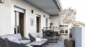 An outdoor patio with wicker furniture, a stone floor, and a view of the building's interior. - Nordic spanish pool villa (Campello)
