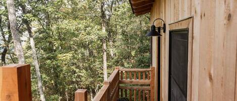 A wooden cabin with a balcony overlooking a forested area.