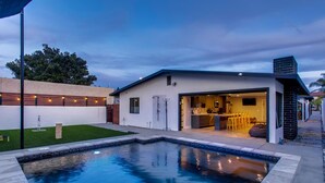 A modern house with a swimming pool, a kitchen, and a dining area.