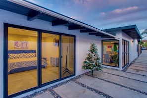 Une maison moderne avec de grandes fenêtres en verre, un petit sapin de Noël et un ciel dégagé.
