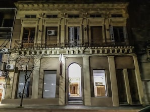 Un edificio histórico con una entrada central, ventanas grandes y un balcón con barandillas.