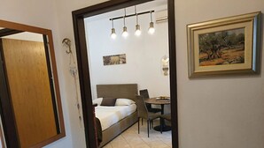 A bedroom with a bed, bedside table, and a desk with a chair. There is a painting on the wall and a door leading to another room. - Apartment in Zaton (Zadar) with Balcony, Air condition, WIFI (4810-2) (Nin)
