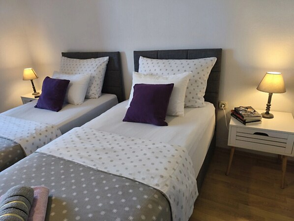 A hotel room with two beds, each with a pillow and a bedside lamp. There is a nightstand with a lamp and books. - Apartment in Zaton (Zadar) with Seaview, Loggia, Air condition, WIFI (4810-3) (Zaton)