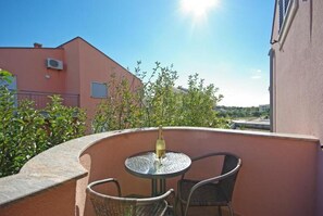 A balcony with a round table and two chairs, overlooking a building and greenery. - Apartment in Zaton (Zadar) with Seaview, Loggia, Air condition, WIFI (4810-4) (Zaton)