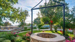 A garden with a stone fire pit, a swing set, and various plants and flowers. - Apartment in Zaton (Zadar) with Seaview, Loggia, Air condition, WIFI (4810-4) (Zaton)