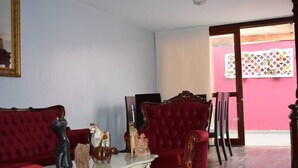 A living room with a red sofa, a matching armchair, and a small table with figurines.