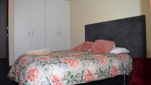 A bedroom with a bed, a large wardrobe, and a dark headboard.