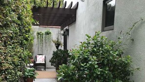 A narrow concrete pathway flanked by potted plants and a wooden pergola. -  Guest house, Historical Area, Close to Beverly Hills,  and Studios (Los Angeles)