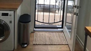 A kitchen with a washing machine, a trash bin, and a door with a metal gate. -  Guest house, Historical Area, Close to Beverly Hills,  and Studios (Los Angeles)