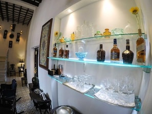 A bar area with shelves of liquor bottles and glasses. - Hostal Real Cervantes (Havana)