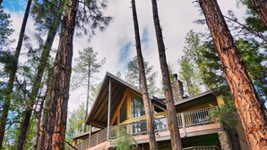 A multi-story lodge with a wooden exterior, balconies, and a hammock in the foreground. - Peaceful Family Mountain Lodge – Theater, Arcade, Hot Tub & Forest Views (Pine)