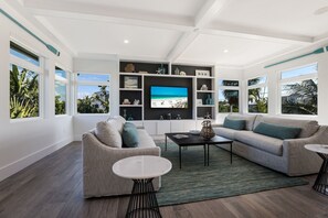 Een moderne woonkamer met een grote televisie, twee banken, een salontafel en een boekenkast.