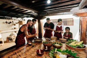 Una cocina rústica con vigas de madera, utensilios colgando y una variedad de ingredientes frescos sobre la encimera.