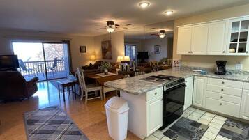 A kitchen with a central island, white cabinets, and a dining area with a table and chairs.