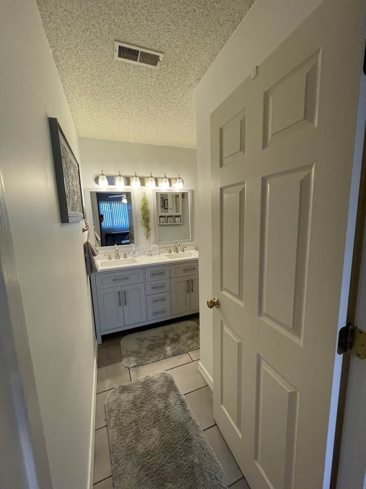 Une salle de bain avec un meuble-lavabo blanc, un miroir et un porte-serviettes.