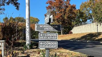 A street sign for Wimbledon Drive with directional arrows to condos numbered 60-63 and 64-69.