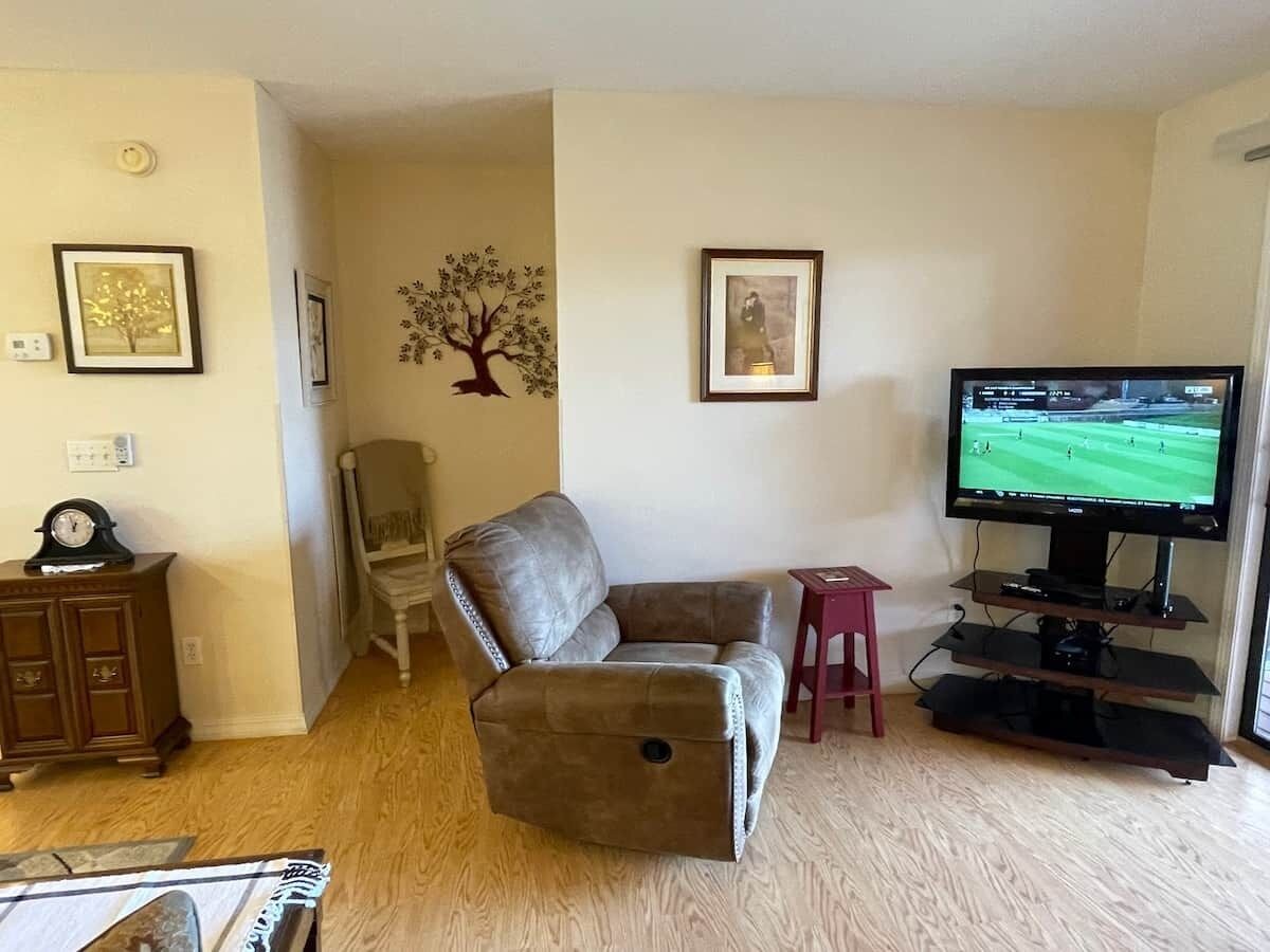 A living room with a leather armchair, a television, a small table, and a cabinet.