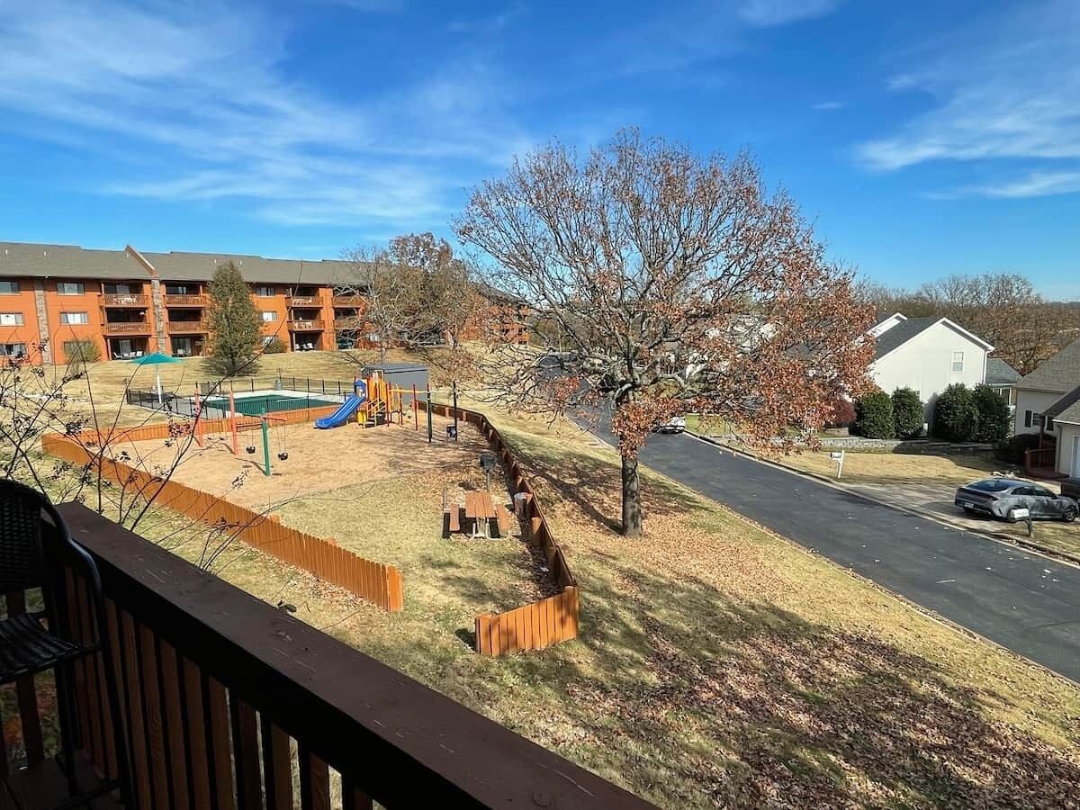 Un quartier résidentiel comprenant une aire de jeux, une rue et un immeuble doté d’un balcon.