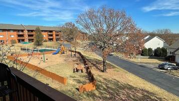 A residential area with a playground, a road, and a building with a balcony.