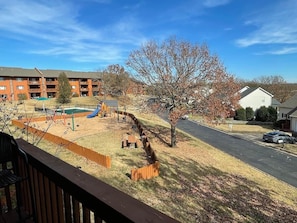 A residential area with a playground, a road, and a building with a balcony.