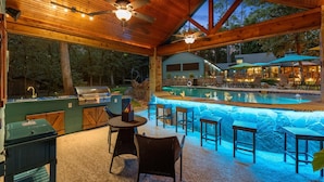 An outdoor pool area with a wooden deck, bar, and seating. - Sleeps 15 | Private custom pool | Hot Tub on 7 Secluded Acres (Holly Lake Ranch)
