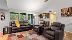 A living room with a brown leather sofa, a matching armchair, and a colorful rug.