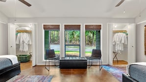 A modern bedroom with a large window, two chairs, a sofa, and a bed. - Sleeps 15 | Private custom pool | Hot Tub on 7 Secluded Acres (Holly Lake Ranch)