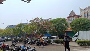 A street scene with parked motorcycles, a white van, and a person walking. - Ratana Cengkareng (Jakarta)