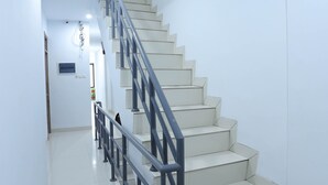 A staircase with a metal railing, white walls, and a tiled floor. - Ratana Cengkareng (Jakarta)
