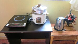 A kitchen with a rice cooker, a coffee pot, and a digital scale on a wooden table.
