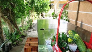 A wooden bench with a floral design, a red basket with plants, and a concrete pathway in a garden area.