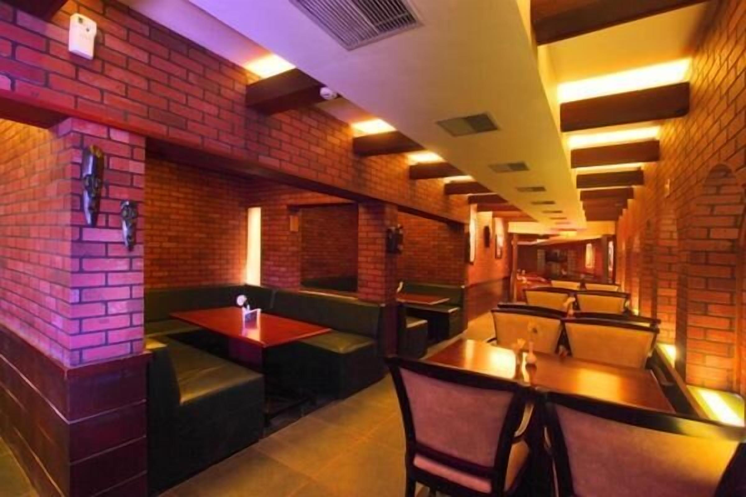 A restaurant with brick walls, booths, and tables.