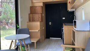 Une cuisine compacte avec des meubles en bois, un four à micro-ondes et un petit coin repas comprenant une table et des chaises.