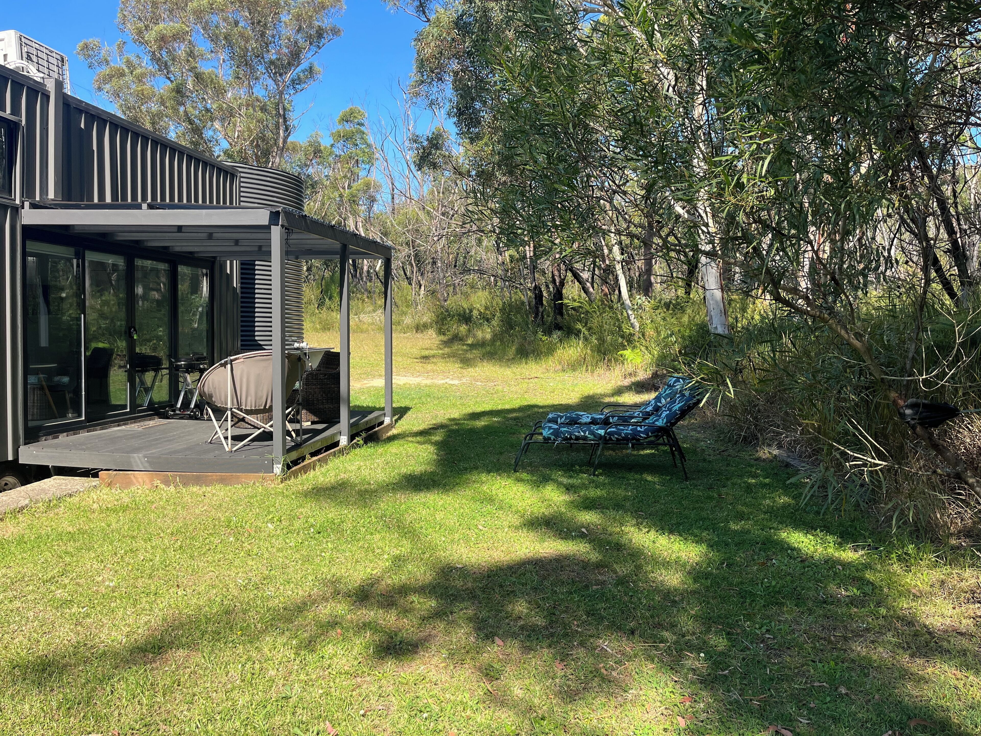 A modern outdoor lounge area with a covered seating area and a lawn chair.