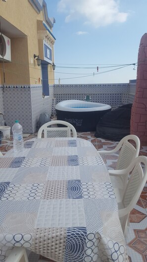A patio with a table and chairs, a water bottle, and a spa tub.