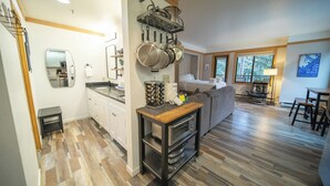 A modern kitchen with a built-in oven, a dining area with a table and chairs, and a large window providing natural light. - Mountain Retreat | Balcony, Hot Tub & Firepit (Keystone)