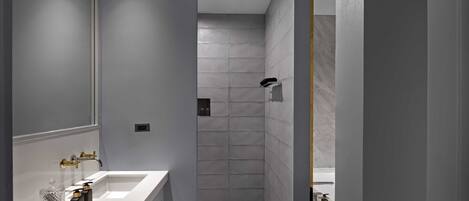 A modern bathroom with a large mirror, a white sink, and a shower area.