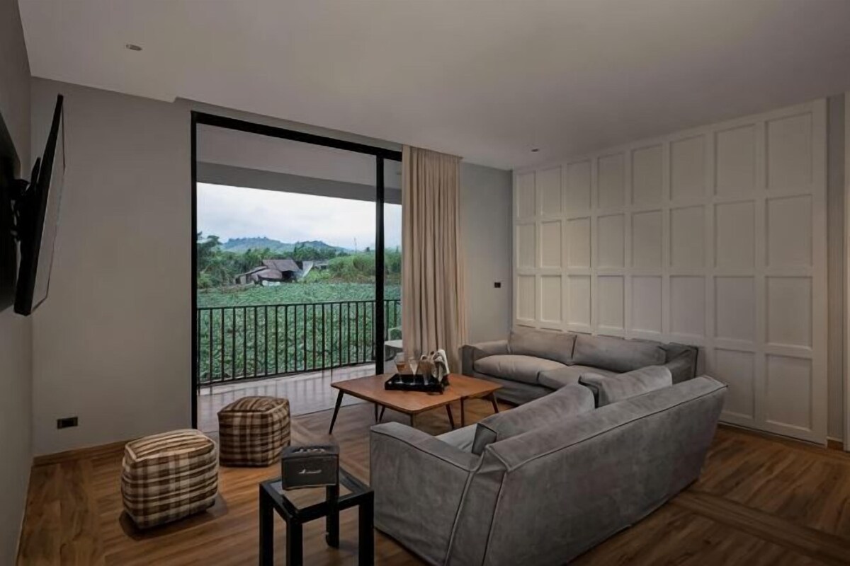A modern living room with a grey sofa, a wooden coffee table, and a large sliding glass door leading to a balcony.