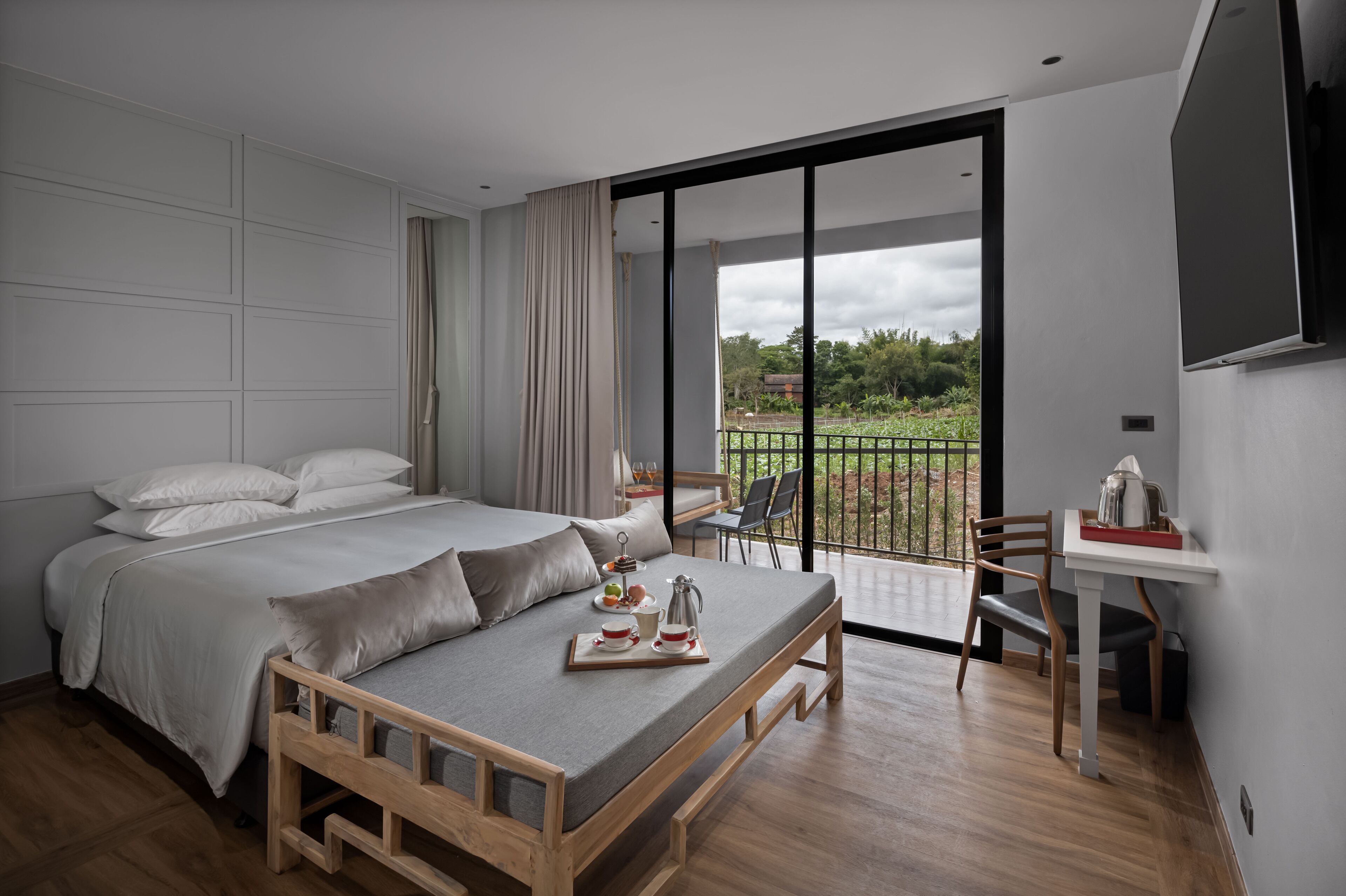 A modern bedroom with a bed, a dining table, and a view of the outdoors.