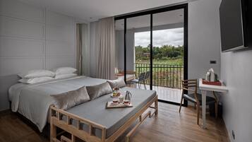 A modern bedroom with a bed, a dining table, and a view of the outdoors.