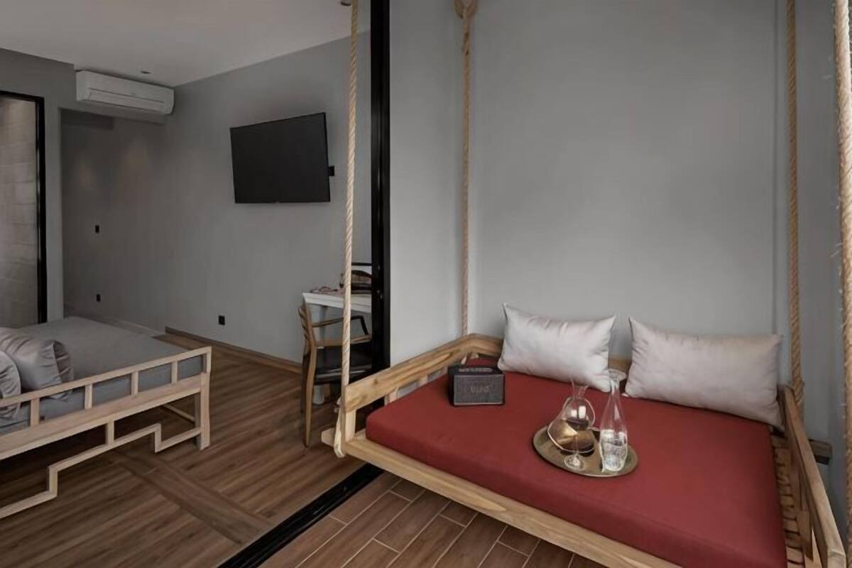 A room with a bed, a desk, a chair, and a television on the wall.