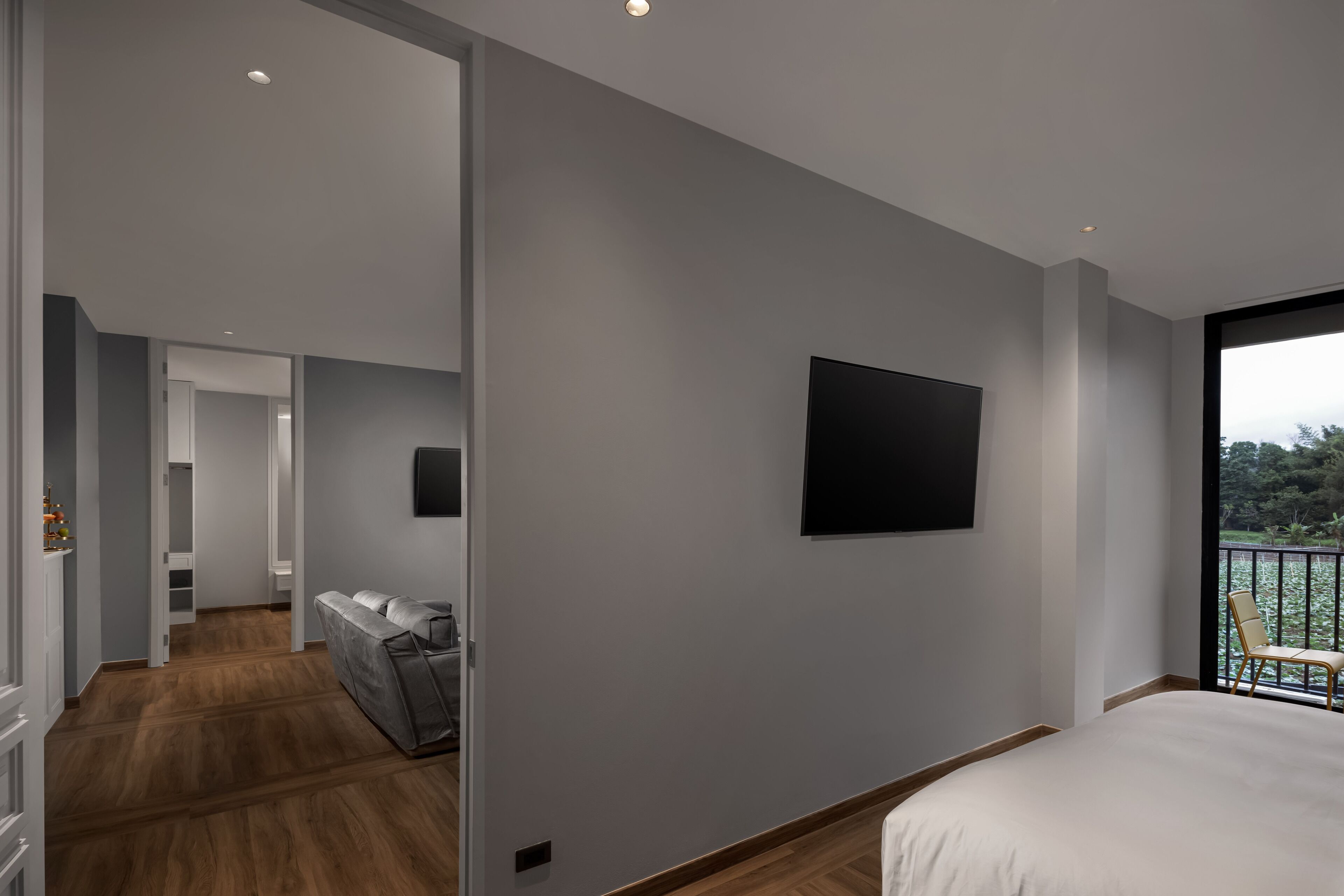 Ein modernes Hotelzimmer mit einem großen Bett, einem flachbildfernseher an der Wand und einem Balkon mit Blick ins Freie.