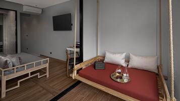 A modern room with a hanging swing bed, a wooden bench, and a flat-screen TV.
