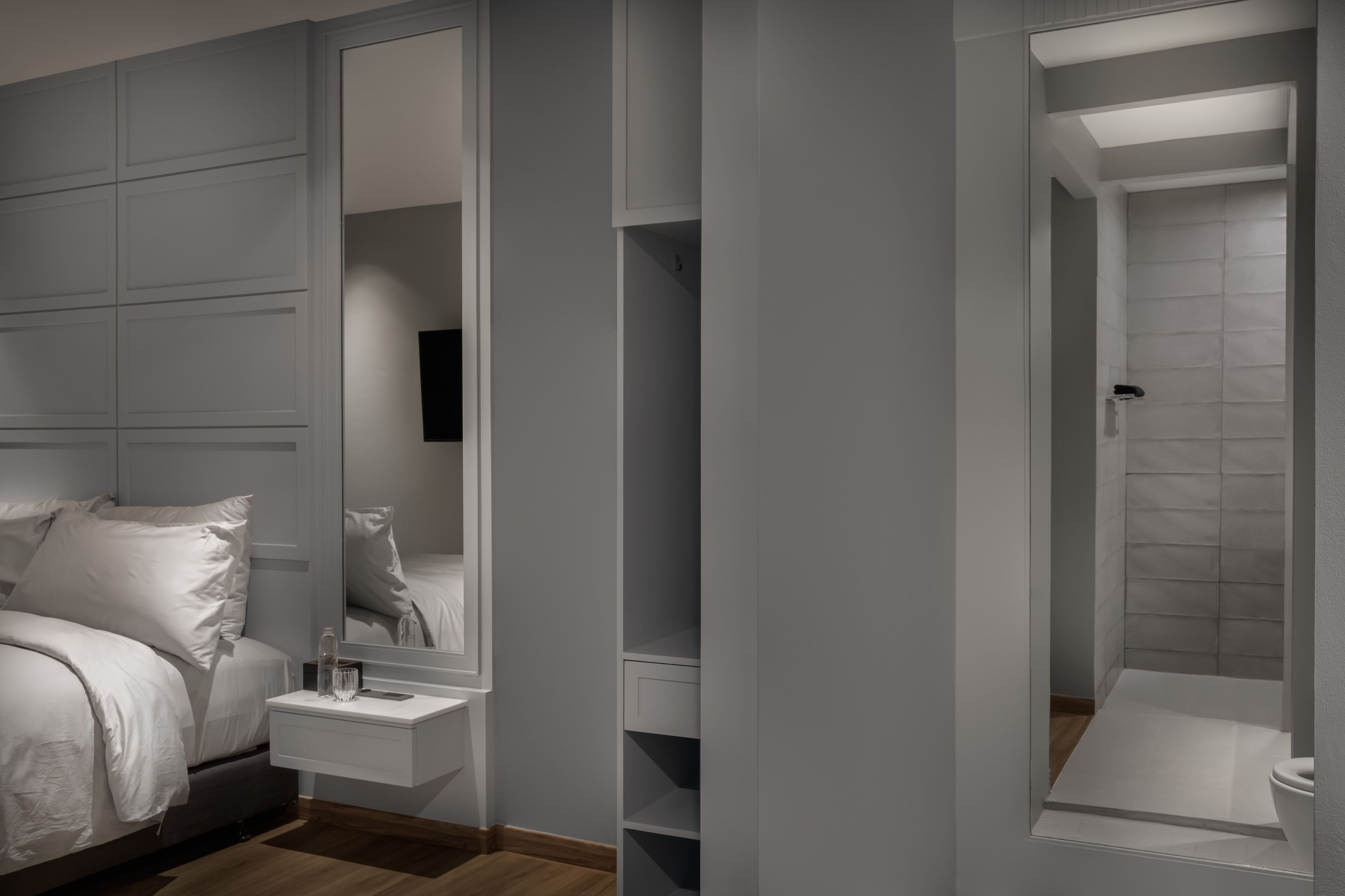 Un dormitorio moderno con cama, mesita de noche y un espejo grande.