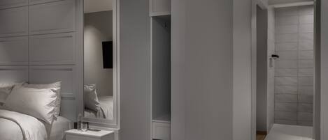 Un dormitorio moderno con cama, mesita de noche y un espejo grande.
